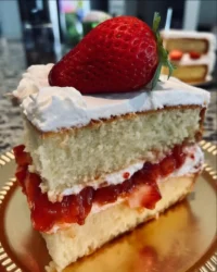 A slice of classic vanilla butter cake with fluffy white frosting on a ceramic plate