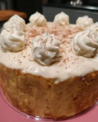 Whole eggnog cake topped with pecans and creamy frosting on a cake stand