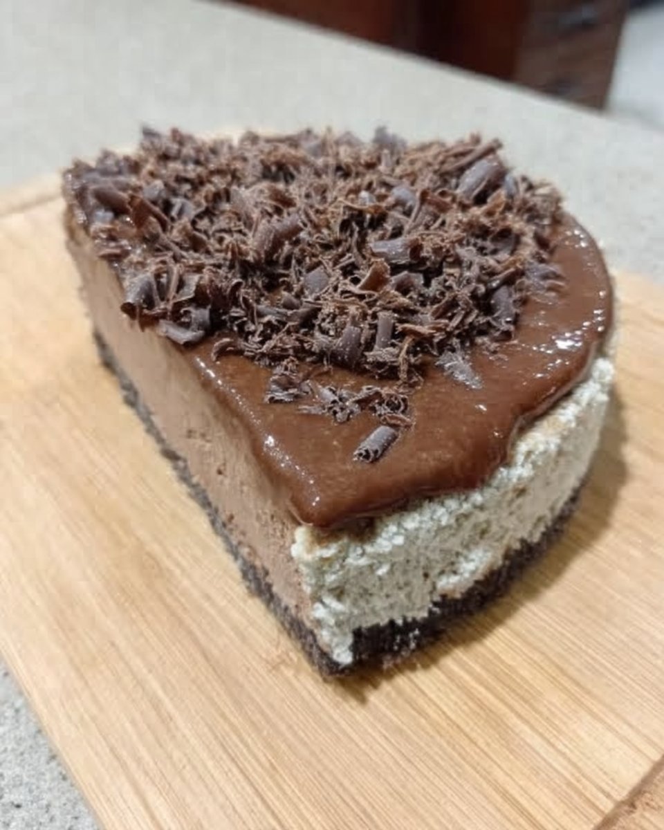 Slice of rich chocolate cheesecake with glossy ganache on a plate