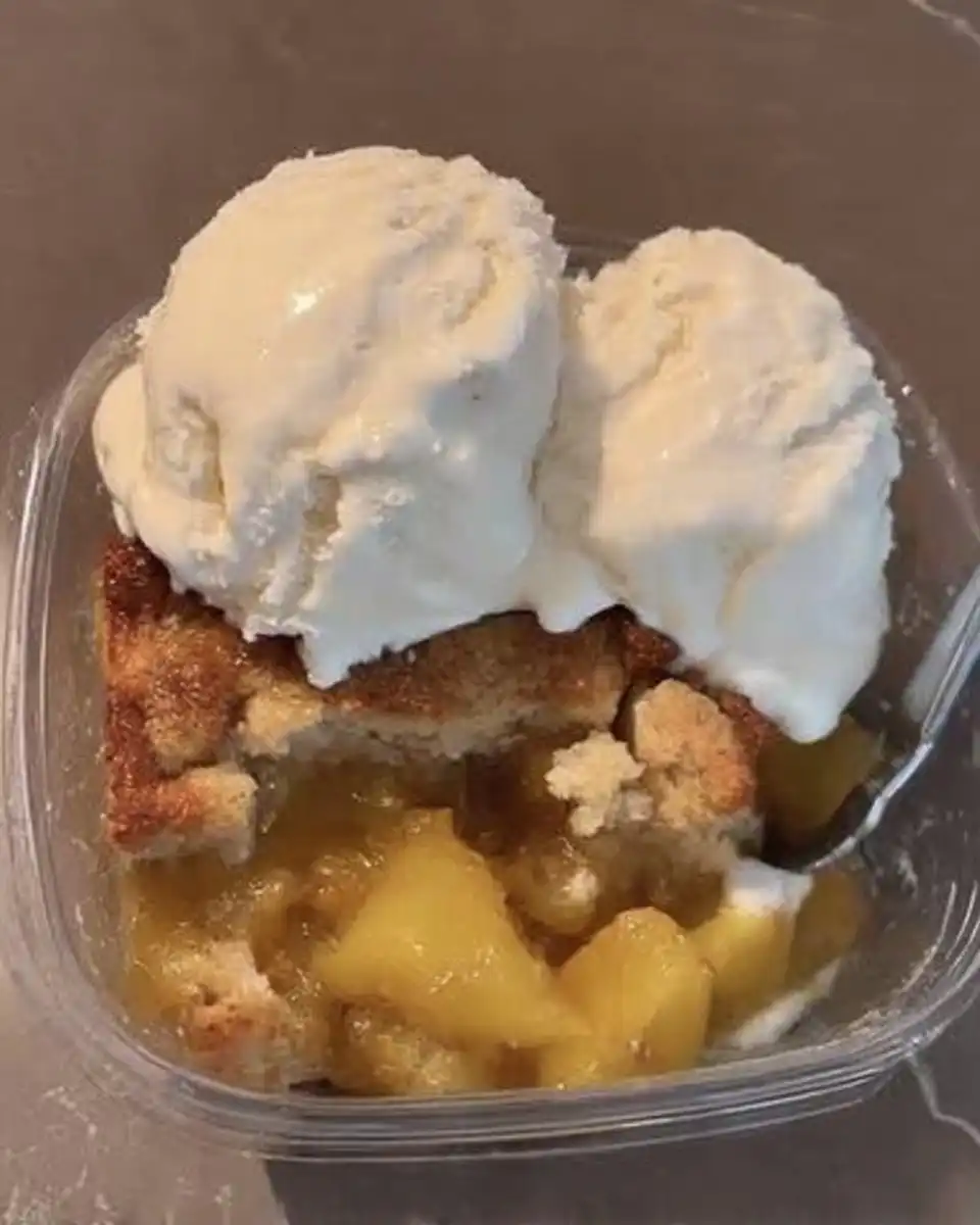 Spatula folding chopped peaches into thick cake batter in a mixing bowl