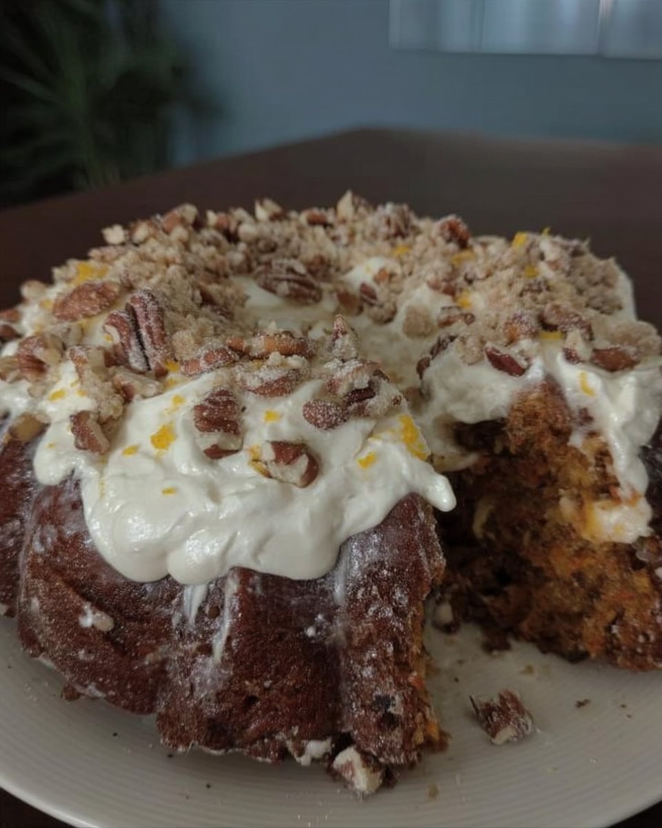 Slice of moist carrot cake with whipped cream cheese frosting on a ceramic plate.