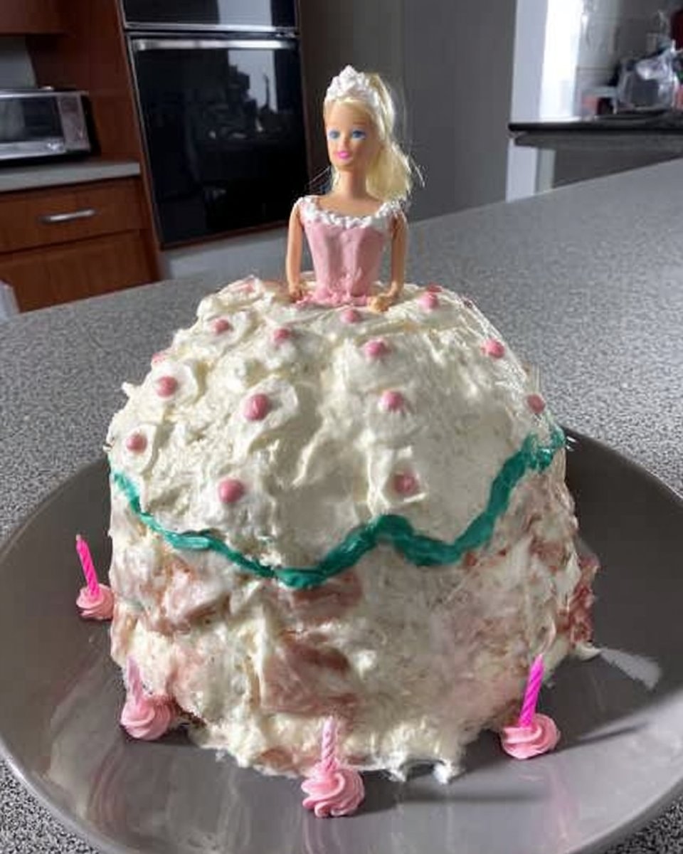 A vintage style barbie cake with pink ruffled frosting on a glass stand