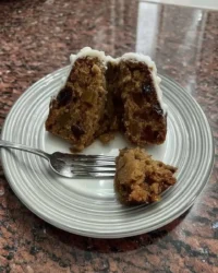 Vintage dark fruitcake loaf topped with pecans on a rustic wooden board
