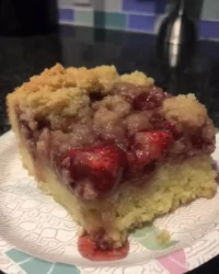 Slice of strawberry rhubarb cake on a vintage floral plate with a fork