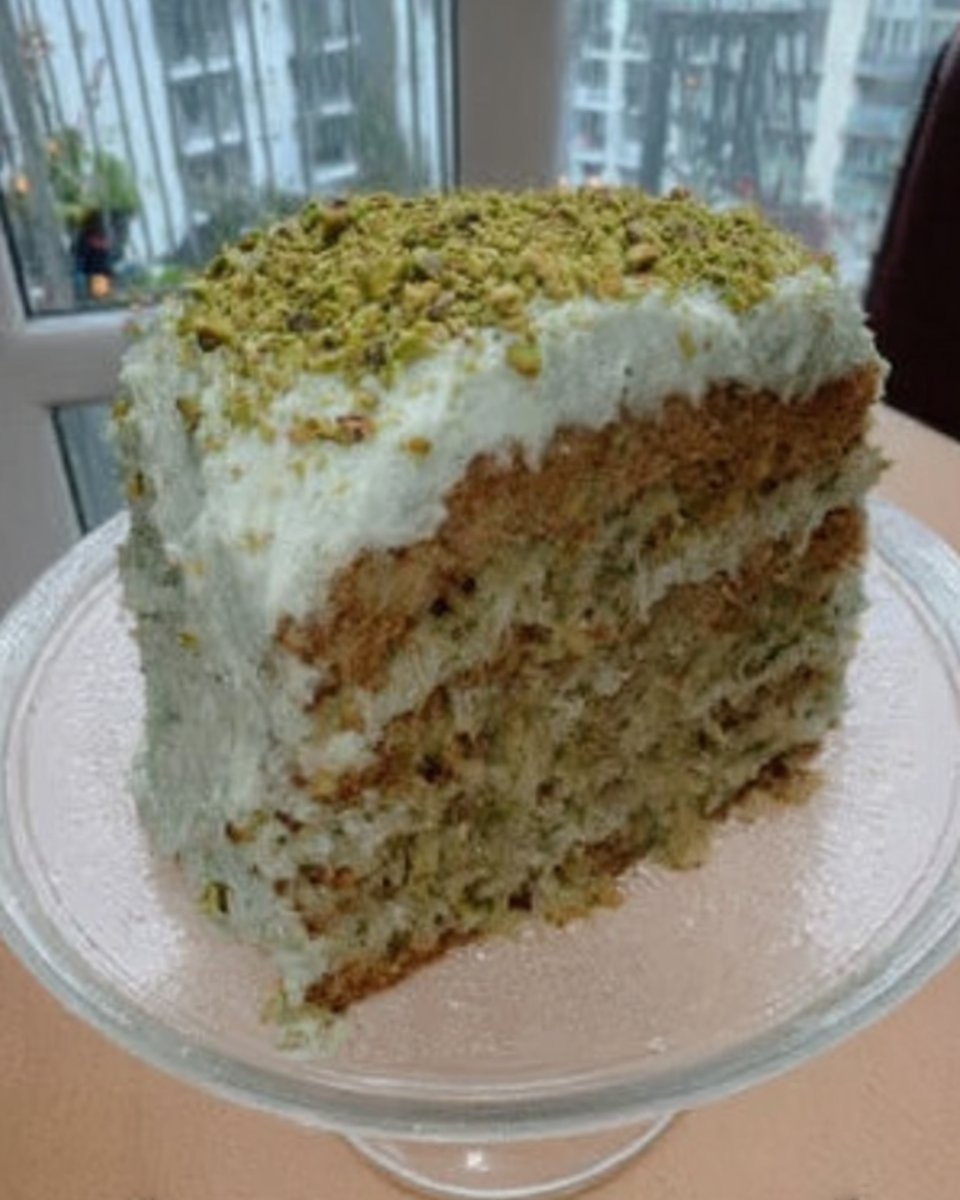 Slice of green watergate cake with pistachio frosting on a vintage floral plate