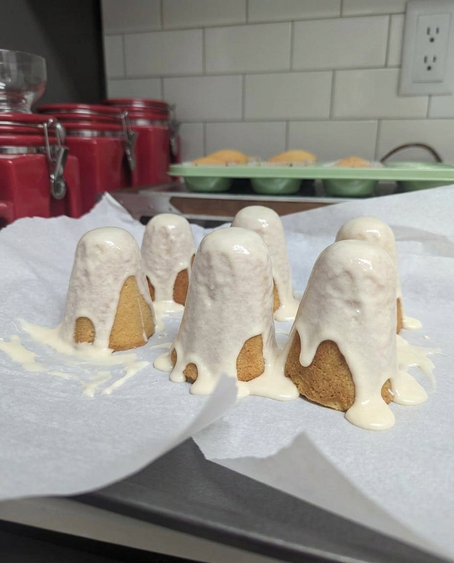A tall 3D ghost cake with white buttercream and black eyes on a black stand