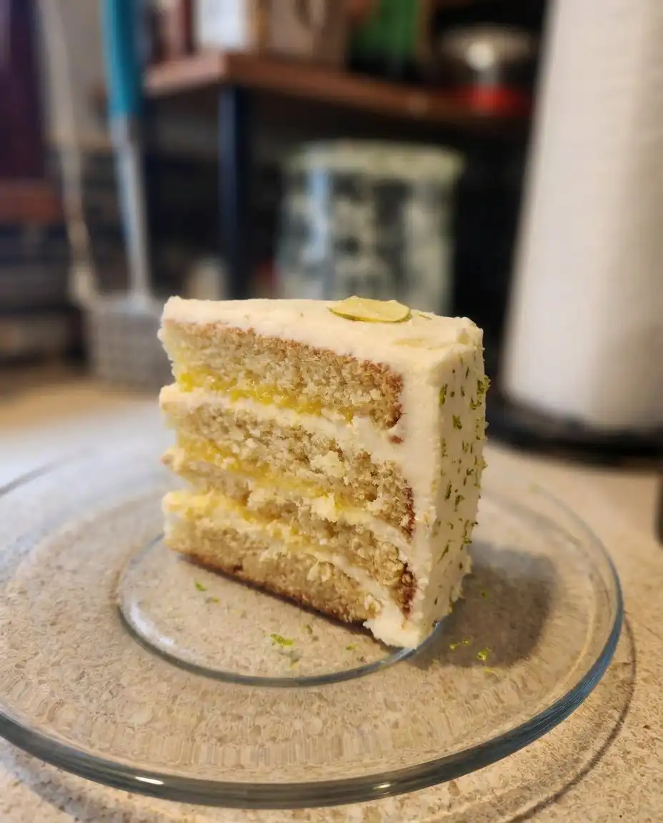 A palette knife spreading smooth cream cheese frosting over a lime cake