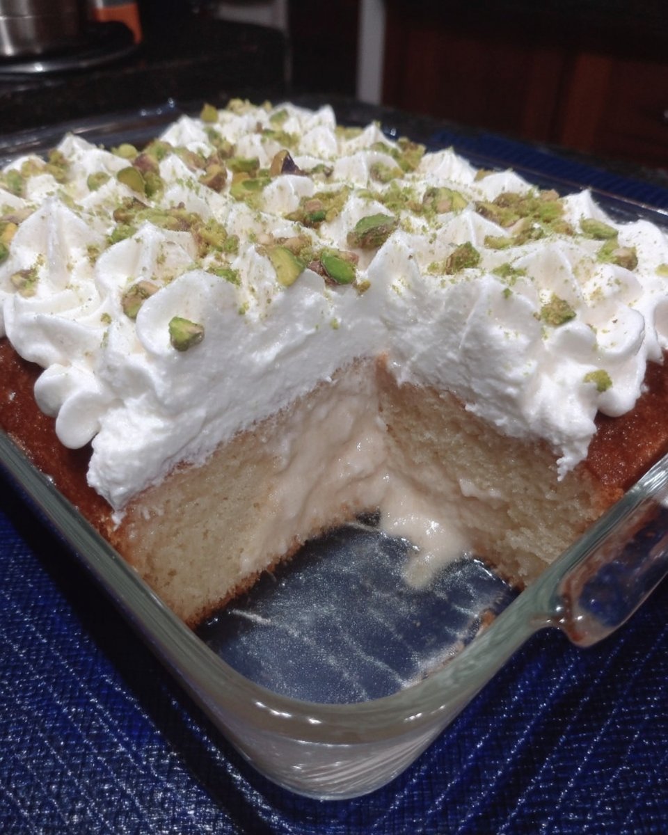 A close up shot of a slice of Tres Leches cake with whipped cream and cinnamon dusting