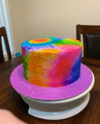 A close up of a palette knife applying a stroke of blue buttercream to a white cake