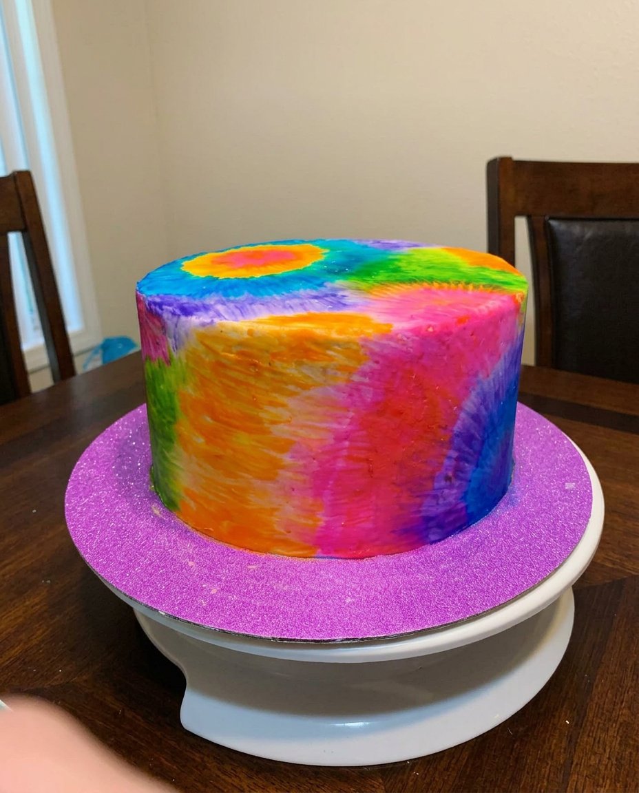 A close up of a palette knife applying a stroke of blue buttercream to a white cake