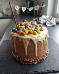 A four layer candy cake sliced open to reveal a hidden center of pastel chocolates and sprinkles