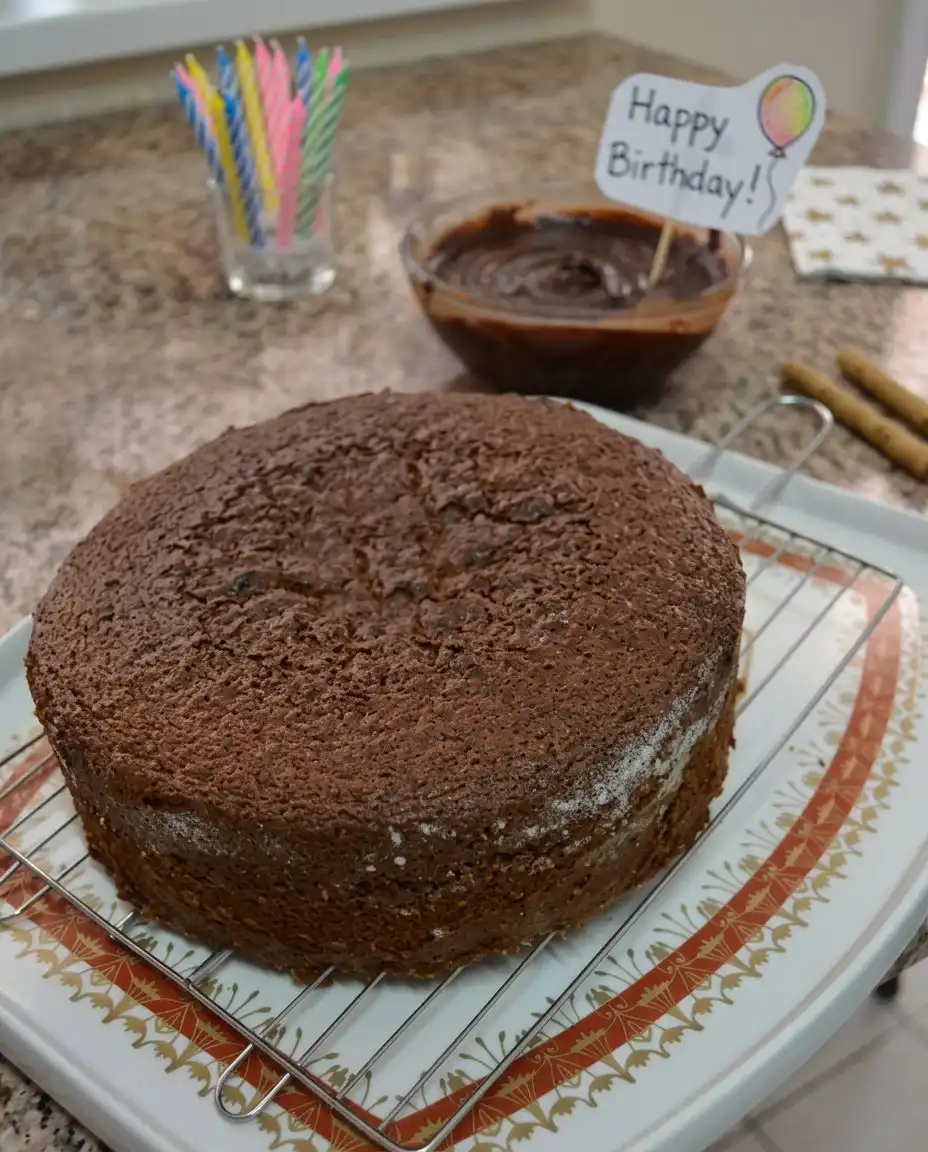 A slice of chocolate cake on a white plate with a gold fork