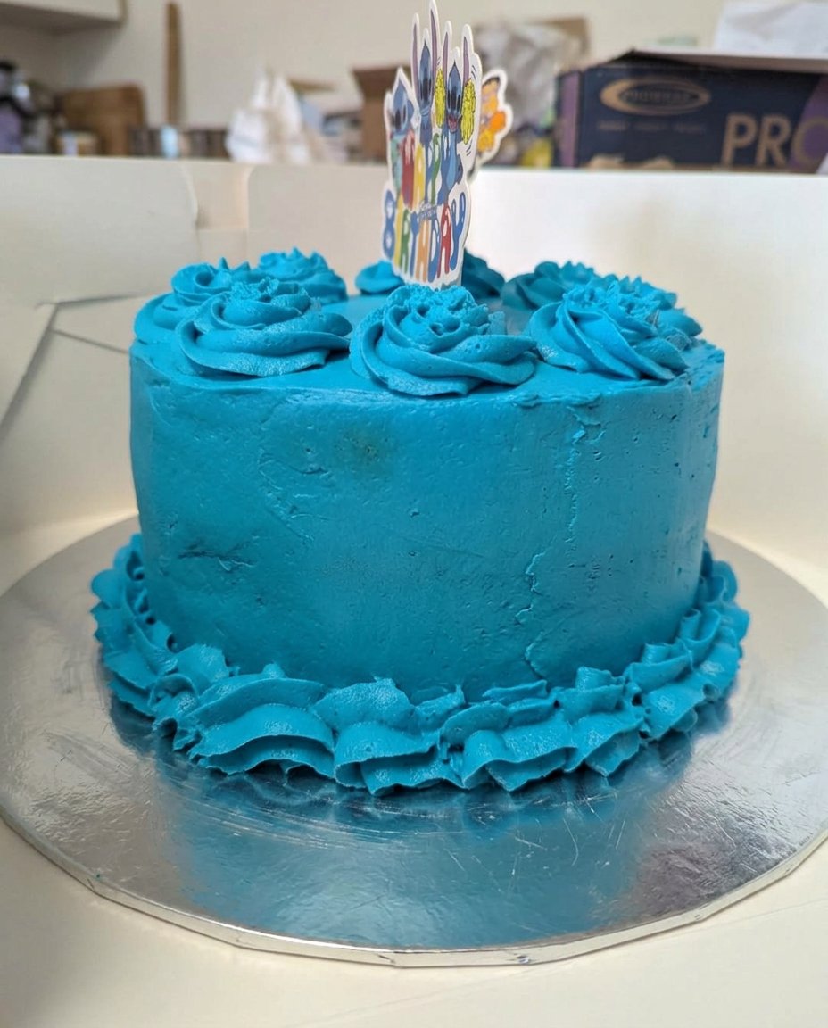 A completed chocolate cake with smooth blue-tinted frosting and fresh cherries on top