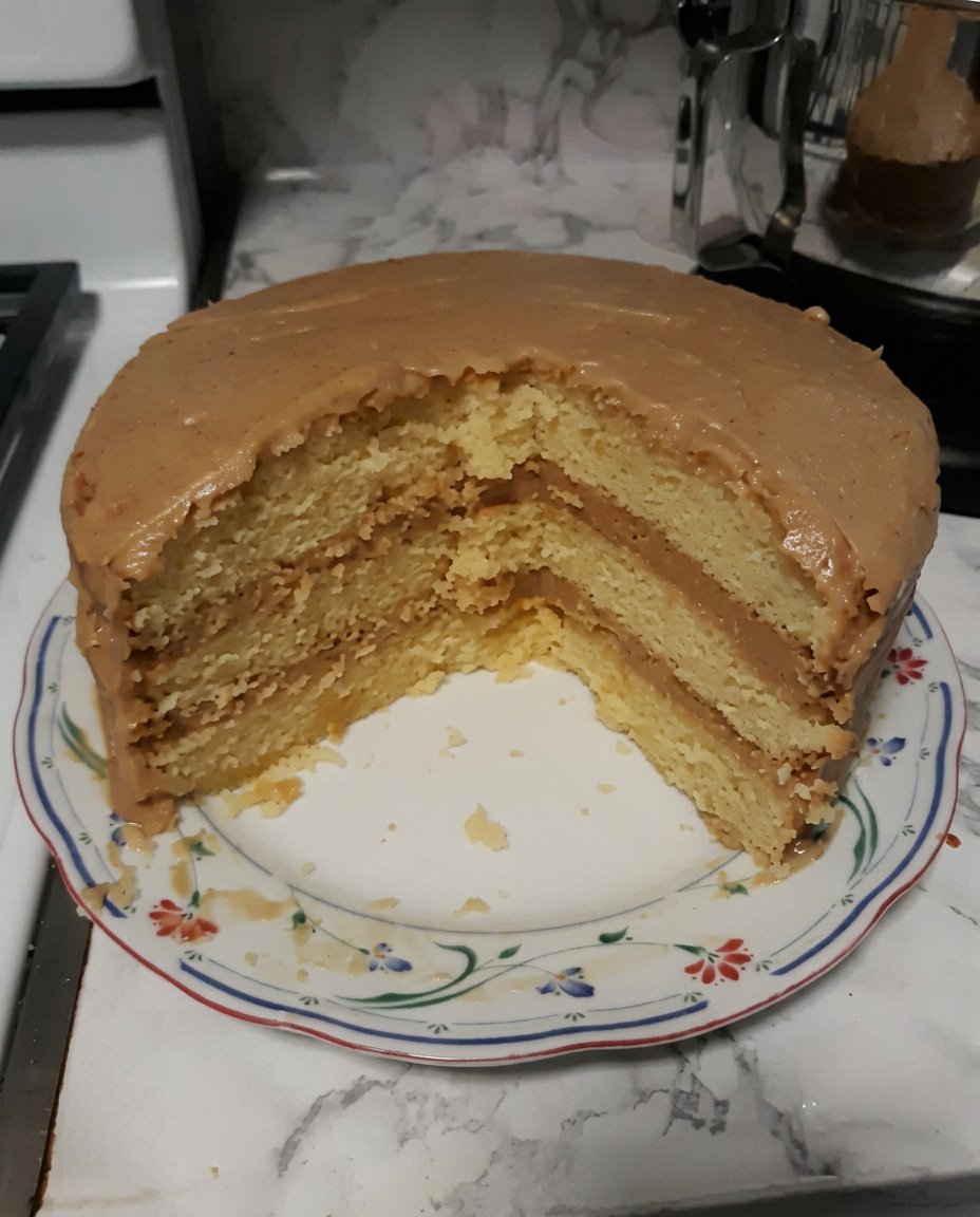 Three tiers of golden caramel cake stacked with rich cooked frosting