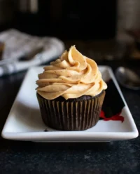 A small 6-inch dark chocolate cake with smooth white frosting on a minimalist stand.