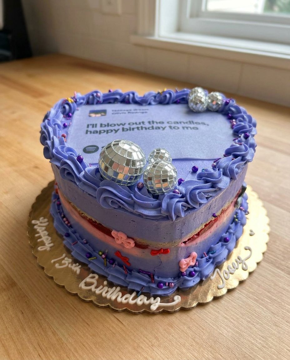 A tall four layer purple Olivia Rodrigo cake with ruffles and ribbons