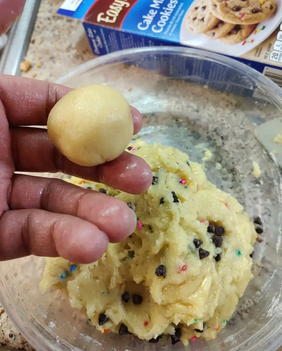 A hand using a circular biscuit cutter to shape a warm cookie into a perfect circle