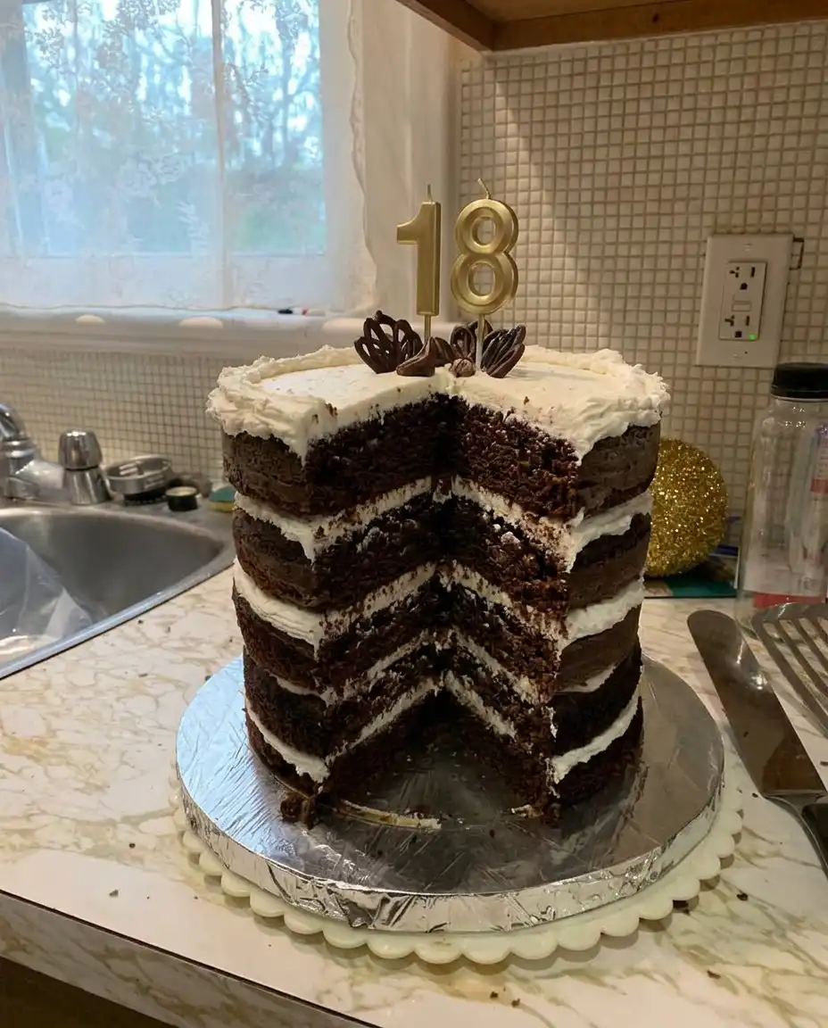 A piping bag adding round dollops of white buttercream to a number shaped sponge cake
