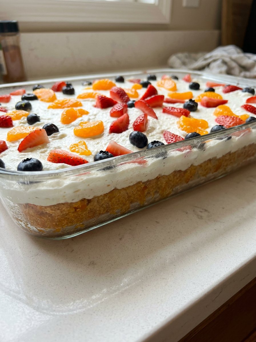 A single slice of mandarin orange cake on a white plate with a fork and mint garnish.