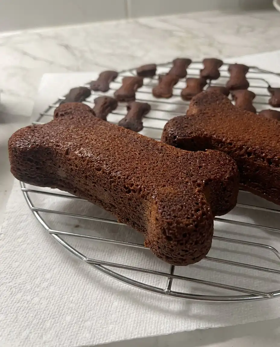 A single slice of carrot peanut butter dog cake served on a white plate next to a gold fork.