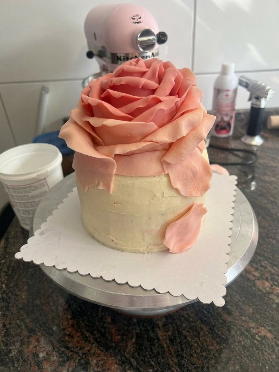 Hands sifting flour into a vintage mixing bowl for a rose cake