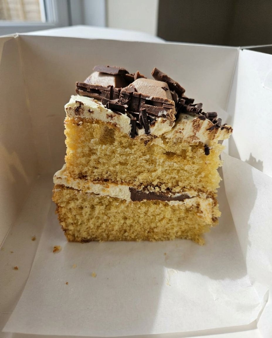 Carrot Cake Slice 13 A hand using an offset spatula to spread cream cheese frosting over a cooled cake