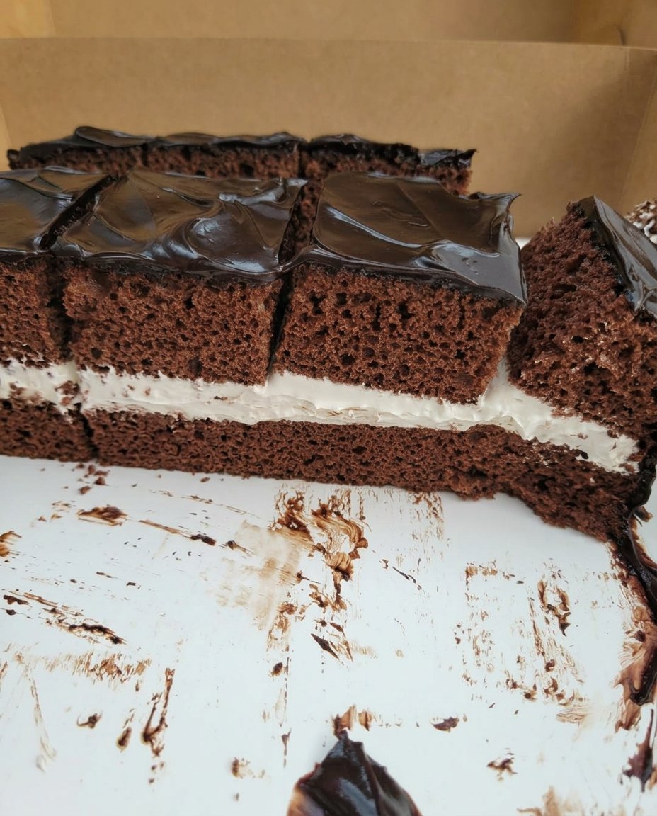A single slice of square chocolate cake with thick frosting on a vintage floral plate