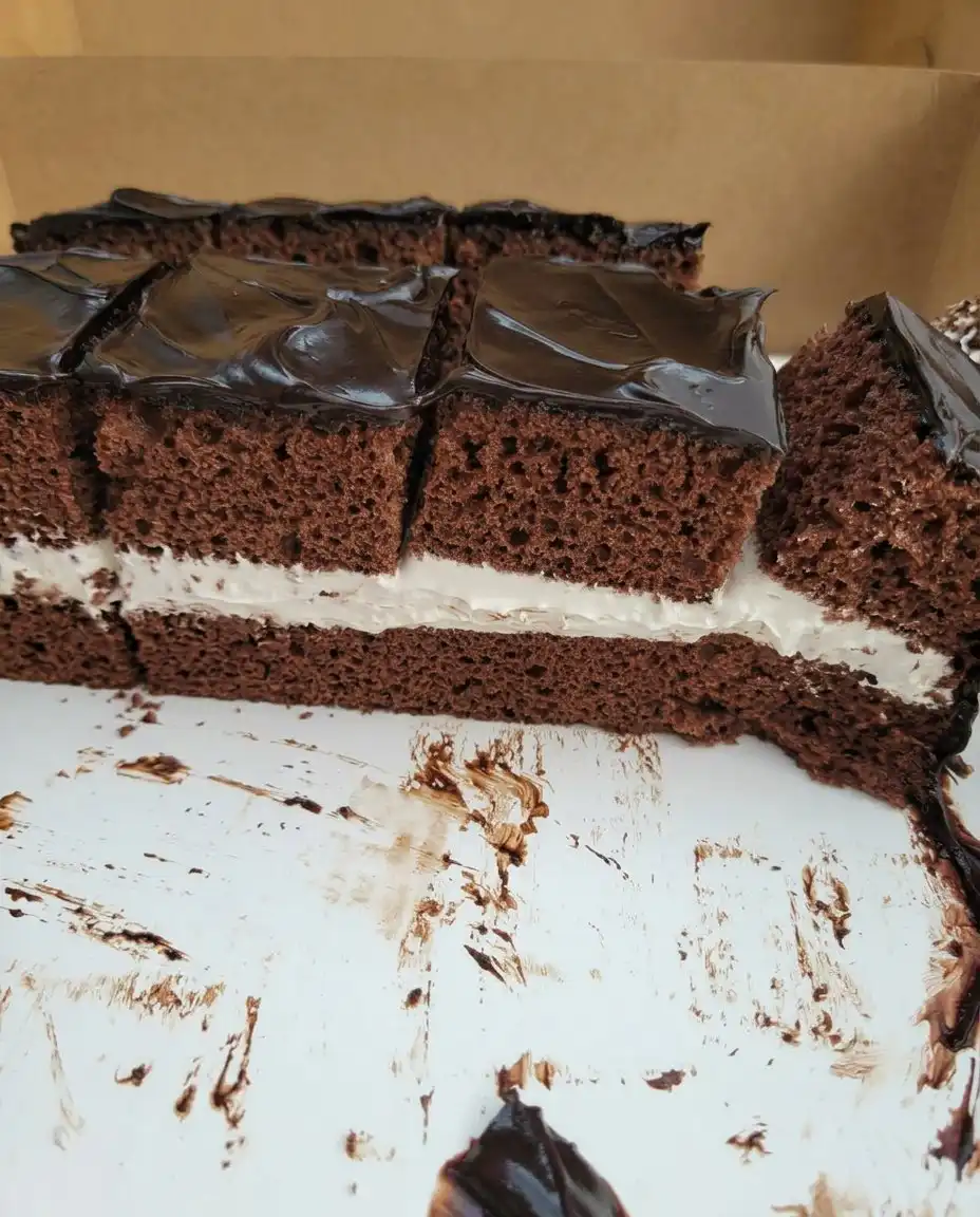 A single slice of square chocolate cake with thick frosting on a vintage floral plate