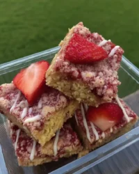 A slice of strawberry crunch cake with pink crumbs on a vintage floral plate
