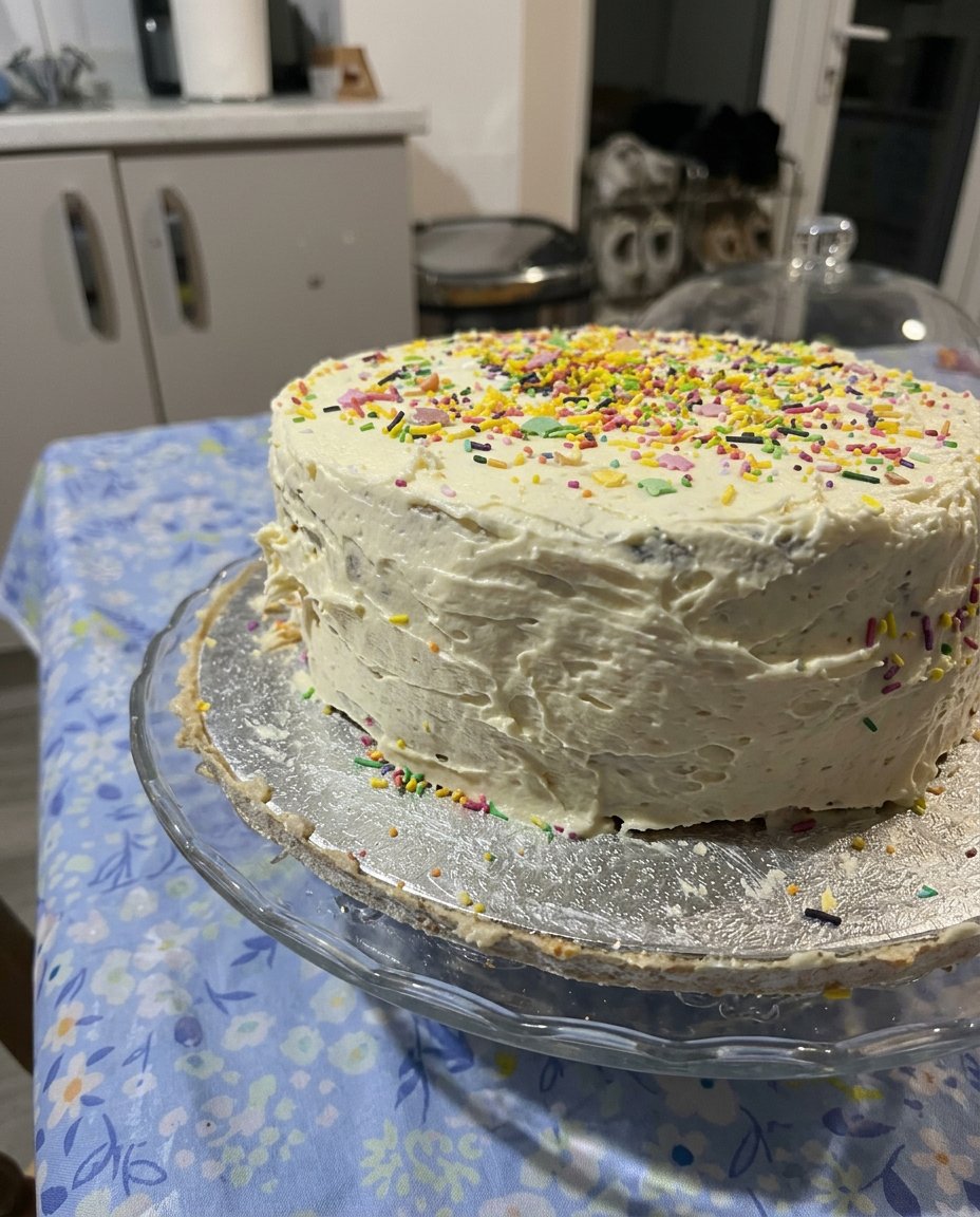Two layer vanilla birthday cake with smooth chocolate frosting on a marble stand