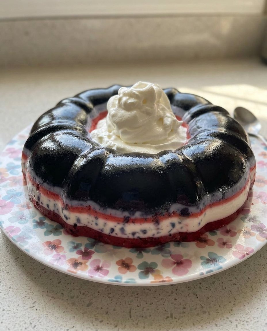 A multi-layered strawberry jello cake in a bundt shape with fresh strawberries