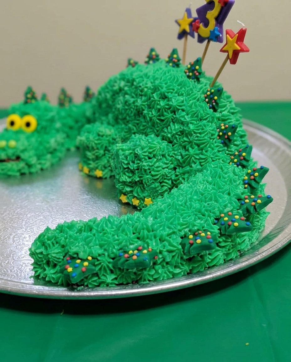 A two layer chocolate cake with vibrant turquoise icing and dinosaur figurines wearing party hats.