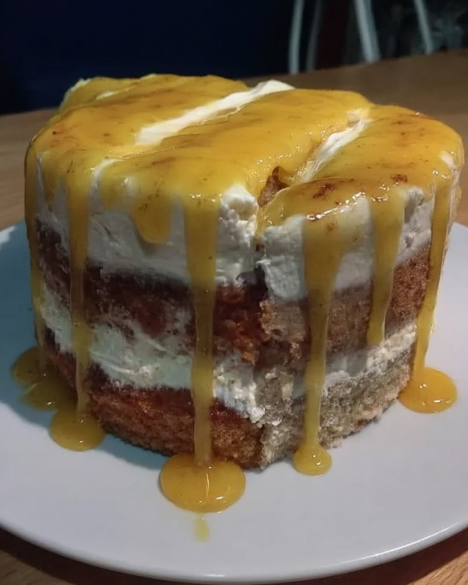 A three-layer lemon rainbow cake with orange frosting on a vintage floral cake stand
