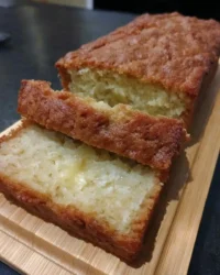 A slice of golden lemon yogurt cake with white glaze on a vintage china plate