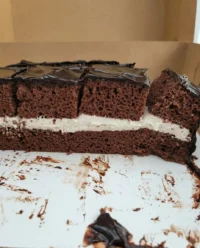 A freshly baked square chocolate cake cooling on a wire rack in a rustic kitchen