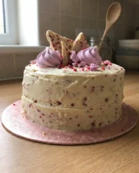 A vintage strawberry prosecco cake sitting on a white lace tablecloth with a silver server.