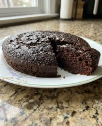 A moist slice of vegan chocolate cake sitting on a vintage floral china plate.
