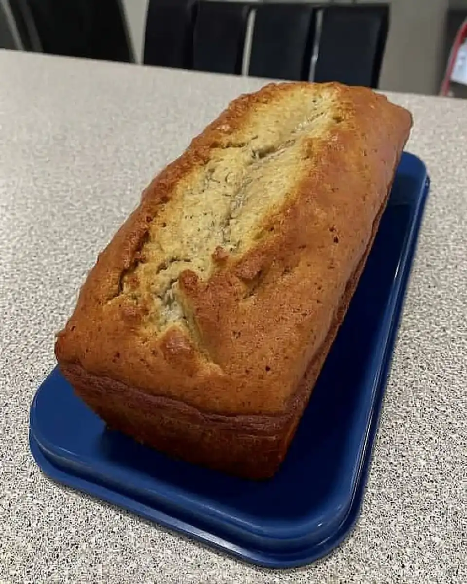 A hand whisking pale yellow cake batter in a large ceramic bowl