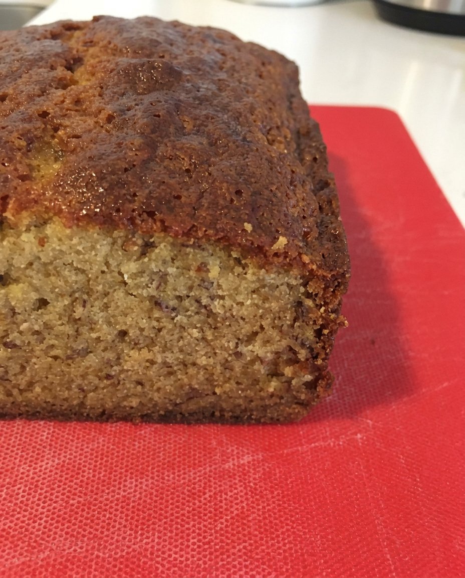 Two loaves of banana coffee cake with a thick cinnamon crumb topping on a wooden board