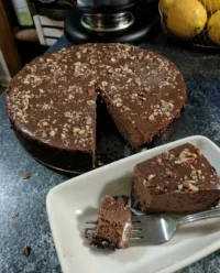 A close up view of a sliced chocolate truffle cake showing the dark sponge and whipped truffle layer