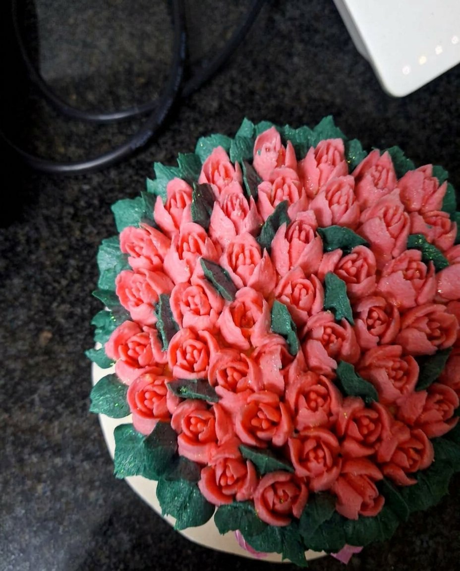 Close up of a piping bag fitted with tip 352 filled with moss green buttercream for leaf work