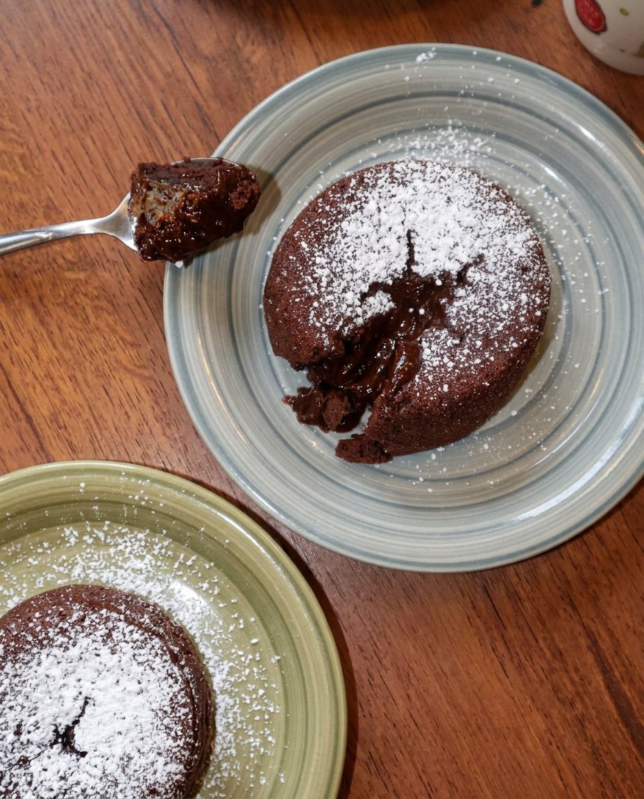 An elegant chocolate lava cake garnished with fresh raspberries and powdered sugar