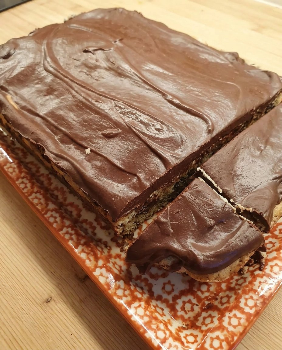A single slice of chocolate ganache cake on a floral vintage plate with a silver fork.