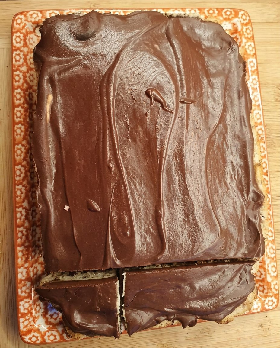 A moist 8-inch chocolate cake covered in glossy dark chocolate ganache resting on a white lace tablecloth.