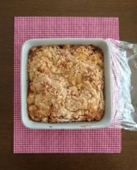 A golden brown strawberry rhubarb cake sitting in a vintage 9x13 glass baking dish on a wooden table.