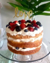 A beautifully assembled angel food cake layered with whipped almond cream and topped with fresh strawberries, blueberries, and raspberries.