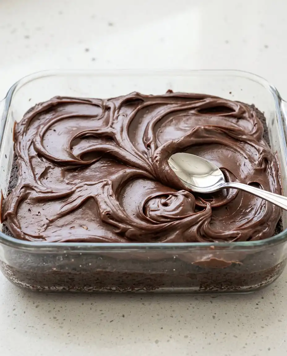 A baker whisking the batter for a Vegan Chocolate Zucchini Cake in a large bowl.
