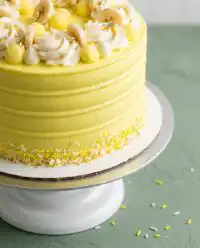 A professional Banana Pudding Layer Cake with yellow frosting and vanilla wafer decorations.