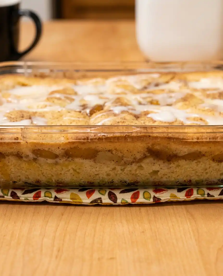 A close up of a hand using a pastry brush to baste Peach Coffee Cake with melted butter.