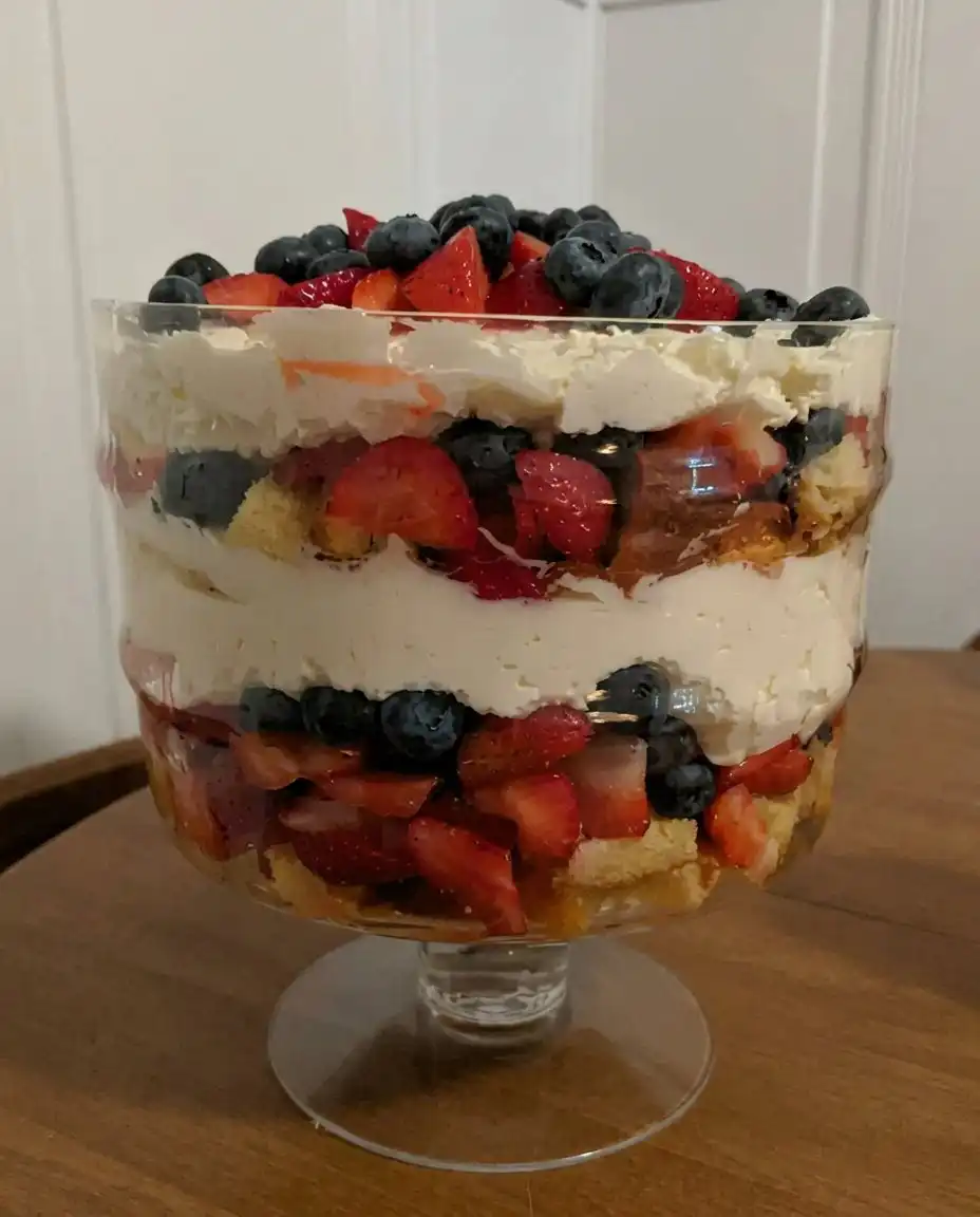 A delicate glass plate holding a perfectly scooped portion of red, white, and blue layered dessert.